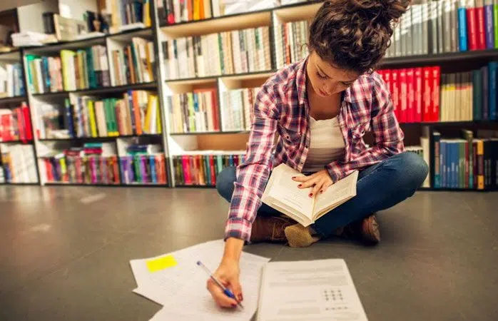 A woman making notes on a Suffolk library floor.